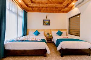 a bedroom with two beds and a wooden ceiling at Tam Coc Green Mountain Homestay in Ninh Binh