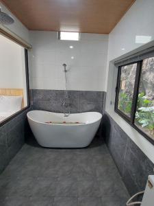 a white tub in a bathroom with a window at Tam Coc Green Mountain Homestay in Ninh Binh