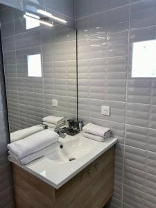 ein weißes Badezimmer mit einem Waschbecken und einem Spiegel in der Unterkunft Confortable appt proche plage Pontaillac à Royan in Royan
