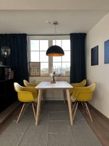 ein Esszimmer mit einem Tisch und gelben Stühlen in der Unterkunft Weimarer Modern Woody Apartment in Buttelstedt