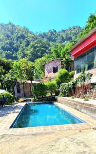 a swimming pool in front of a house at Aum 108 Retreat - Rishikesh Mountains in Rishīkesh