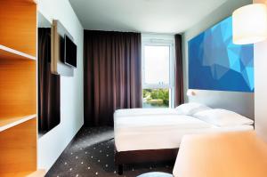 a hotel room with two beds and a window at B&B Hotel Frankfurt-Airport in Frankfurt/Main