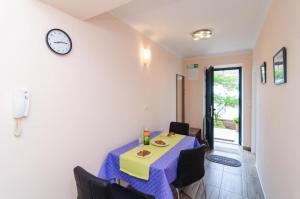 a room with a table with chairs and a clock at Apartments Lena & Lara in Dubrovnik