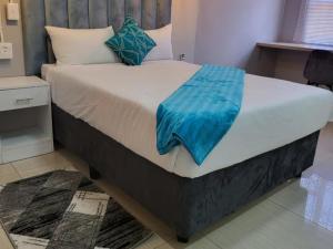 a bed with a blue blanket on it in a room at Early Bird B&B in Nqutu