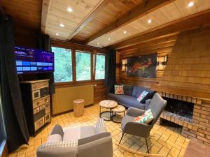 a living room with a tv and a couch and a fireplace at LE RENARD Chalet en bois in La Bresse