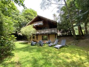 a group of chairs sitting in the grass in front of a house at LE RENARD Chalet en bois in La Bresse