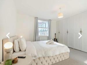 a white bedroom with a white bed and a table at Stunning 2 bedroom flat Camden in London