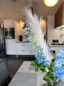 a vase with blue flowers and white feathers in a kitchen at Schlossblick - ABC236 in Zierow