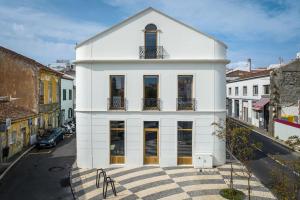 a white building with windows on a city street at The Escape in Ponta Delgada