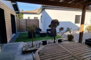 een patio met een houten tafel en stoelen in een tuin bij Jolie maison dans un quartier très calme in Martignas-sur-Jalle