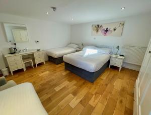 1 dormitorio con 2 camas y lavamanos. en The Queen's Head Hotel, en Buxton