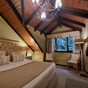 a bedroom with a bed and a chandelier at Altos Los Pioneros & Spa in Villa La Angostura