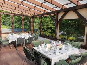 a dining room with white tables and green chairs at Hotel Holter Schloßkrug in Schloß Holte-Stukenbrock