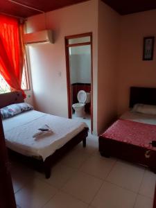 a bedroom with two beds and a toilet and a mirror at Samantha Hotel in Paz de Ariporo