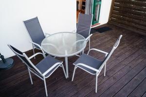 a glass table and four chairs on a deck at MeerZeit - Sünnenkieker WE4 - ABC287 in Beckerwitz