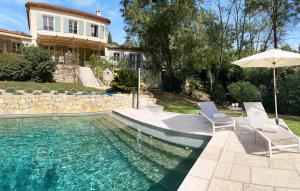 een huis met een zwembad met 2 stoelen en een parasol bij Villamombetti in Montauroux