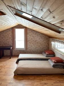 two beds in a room with a ceiling with a window at Daugirdėnų sodyba 