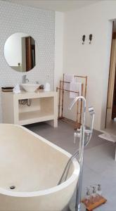 ein Badezimmer mit einer Badewanne, einem Waschbecken und einem Spiegel in der Unterkunft Milavila in Seminyak