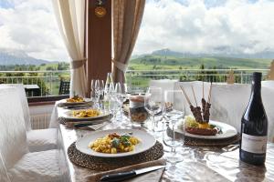 uma mesa com pratos de comida e uma garrafa de vinho em Appartaments Alpi em Seiser Alm
