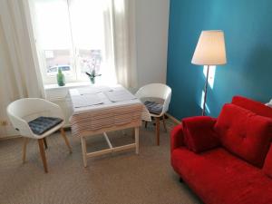 ein Wohnzimmer mit einem roten Sofa, einem Tisch und Stühlen in der Unterkunft Isensee - ABC322 in Wismar