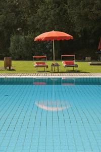 2 sillas y sombrilla junto a la piscina en Frassanelle, en Rovolon