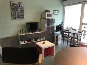 uma sala de estar com uma televisão e uma mesa e cadeiras em 523 - A ERQUY, proximité centre ville et plage du centre, dans un immeuble tranquille em Erquy