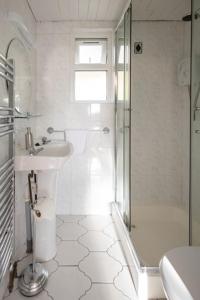 bagno bianco con doccia e lavandino di Summerfield Lodge Garden Cottage a Youghal
