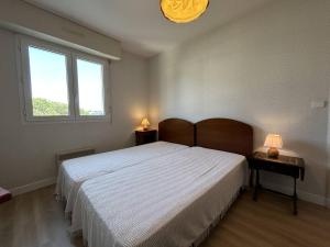 Un dormitorio con una cama grande y dos mesas con lámparas. en 513 - Appartement T3 avec pleine vue mer, en Erquy