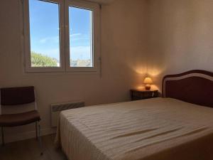 Un dormitorio con una cama y una ventana y una silla. en 513 - Appartement T3 avec pleine vue mer, en Erquy 10 fotos más