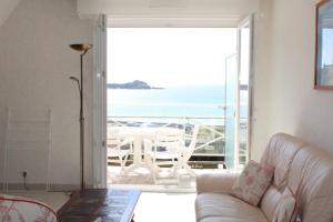 uma sala de estar com um sofá e vista para o oceano em 521 - Bel appartement avec balcon vue mer à Erquy en bordure de la plage du centre et à 300m des commerces em Erquy