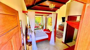 Un dormitorio con una cama con sábanas rojas y una ventana en BANGATACHO - Bangalôs Temáticos na Praia do Patacho - Milagres, en Porto de Pedras