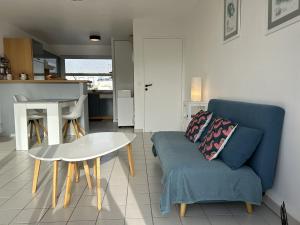 a living room with a blue couch and a table at 527 - T2 en duplex avec vue sur la plage et le Port d'Erquy in Erquy