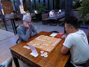 deux hommes assis à une table jouant à un jeu de société dans l'établissement Riverside International Youth Hostel, à Chongqing