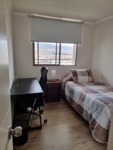 1 dormitorio con escritorio y 1 cama con ventana en El Faro Antofagasta, en Antofagasta