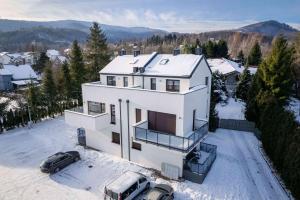 a white house with two cars parked in the snow at Apartamenty Olchowa z tarasem w spokojnej okolicy - Dream Apart in Ustroń