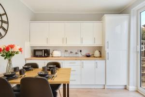 een keuken met witte kasten en een houten tafel bij Elm-G House in Manchester