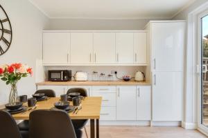 a kitchen with white cabinets and a wooden table at Elm-G House in Manchester