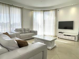 salon z białymi meblami i telewizorem z płaskim ekranem w obiekcie 3BR GARDEN APT GOLF RESIDENCE EILAT w Ejlat
