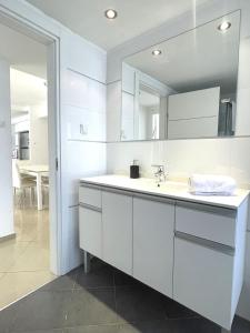 W białej łazience znajduje się umywalka i lustro. w obiekcie 3BR GARDEN APT GOLF RESIDENCE EILAT w Ejlat