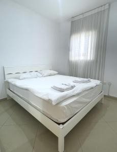 białe łóżko w pokoju z oknem w obiekcie 3BR GARDEN APT GOLF RESIDENCE EILAT w Ejlat