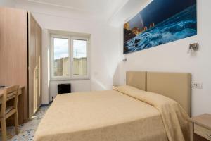 a white bedroom with a bed and a window at Guest House La Piazzetta in Capri