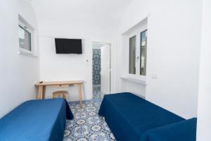a room with two beds and a table and a tv at Guest House La Piazzetta in Capri
