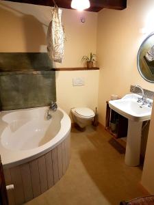a bathroom with a tub and a toilet and a sink at La Ferme De Chalas in Valgorge