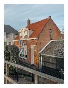 une maison en briques avec une porte blanche et une clôture dans l'établissement Slapen op Tholen, à Tholen