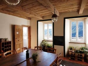 a dining room with a wooden table and windows at La Ferme De Chalas in Valgorge