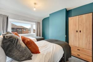 a bedroom with two beds and a blue wall at Elm-G House in Manchester