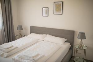 1 cama con sábanas blancas y 2 mesas con lámparas en Auszeit in Radolfzell en Radolfzell am Bodensee