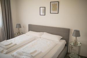 a bed with white sheets and two tables with lamps at Auszeit in Radolfzell in Radolfzell am Bodensee