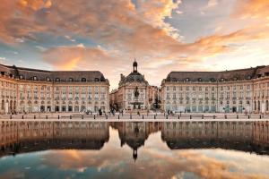 un grand bâtiment avec une réflexion dans l'eau dans l'établissement Key to Bordeaux - fairytale view, 2 bd + elevator, à Bordeaux