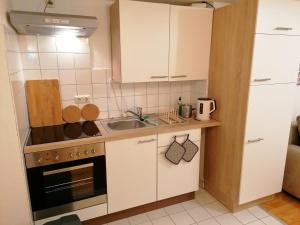 una piccola cucina con armadi bianchi e lavandino di Marienblickappartement - ABC269 a Wismar